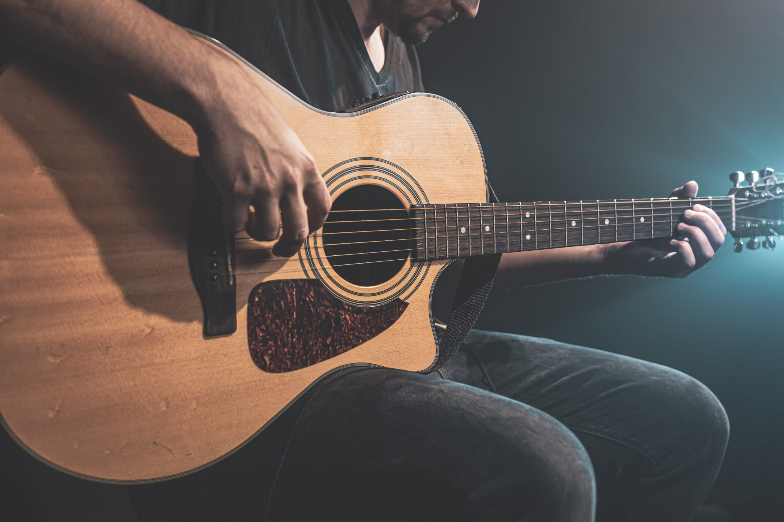primer plano hombre tocando guitarra acustica oscuridad iluminacion escenica 1 scaled - Mejores Accesorios para Guitarra